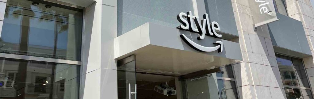 Entrance of a store with large glass windows and a sign that reads "style" with an Amazon smile logo.