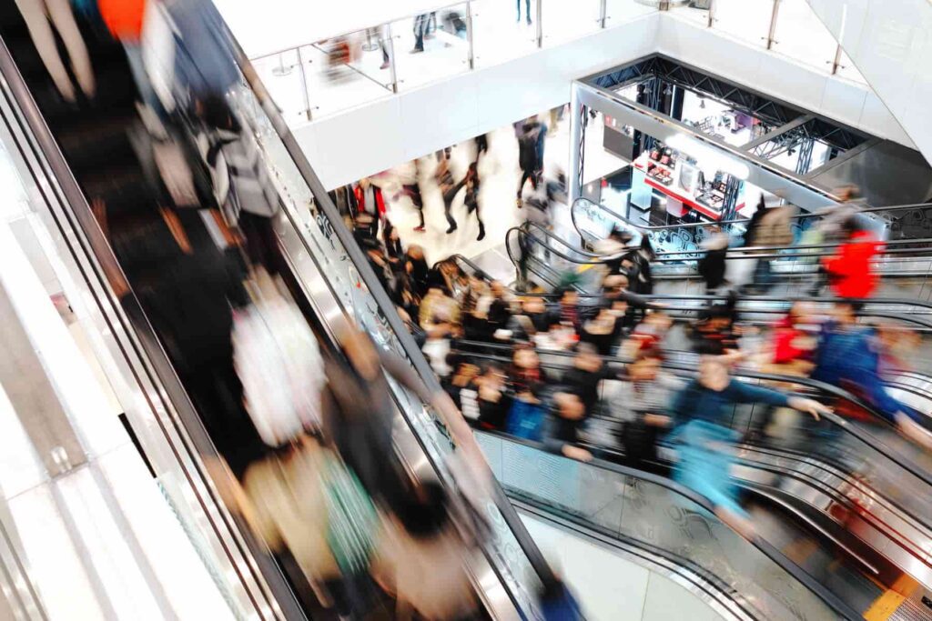 A busy shopping mall with people on escalators.
