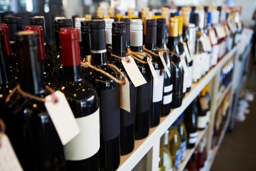 Rows of assorted wine bottles with blank tags on a store shelf.