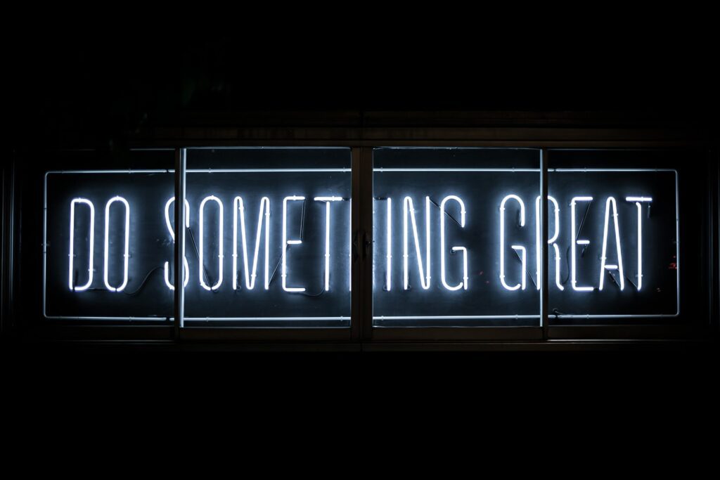 A neon sign glows with the words "DO SOMETHING GREAT" in white capital letters against a dark background.