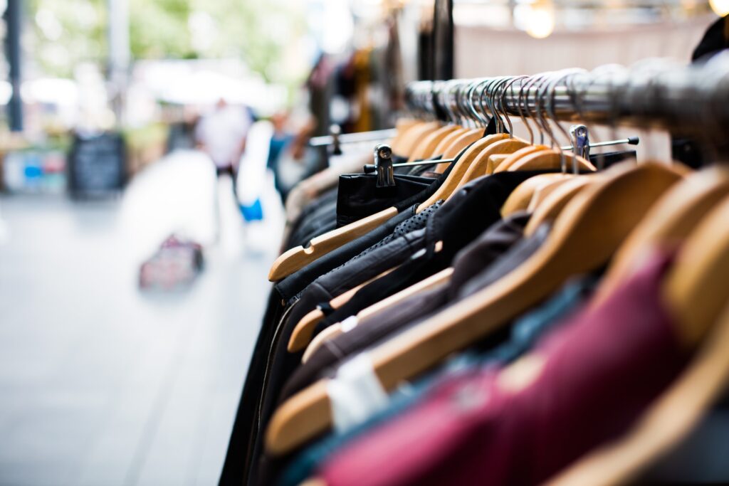 Clothes on wooden hangers displayed on a rack in an outdoor setting.