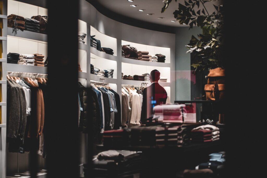 Clothing store interior with neatly arranged garments on shelves and racks, and a mannequin dressed in a red outfit.