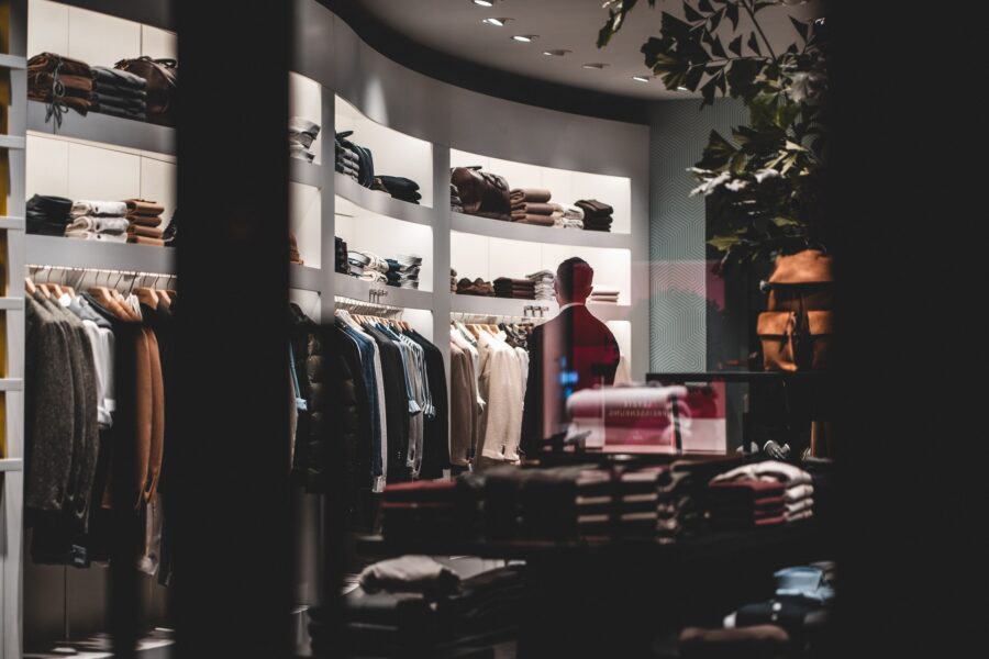 Clothing store interior with neatly arranged garments on shelves and racks, and a mannequin dressed in a red outfit.