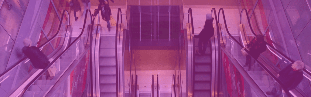 People use escalators in a brightly lit station, with a purple filter effect over the image.