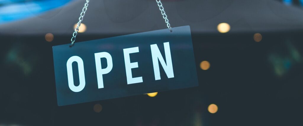 A hanging sign reads "OPEN" against a blurred dark background with round lights.