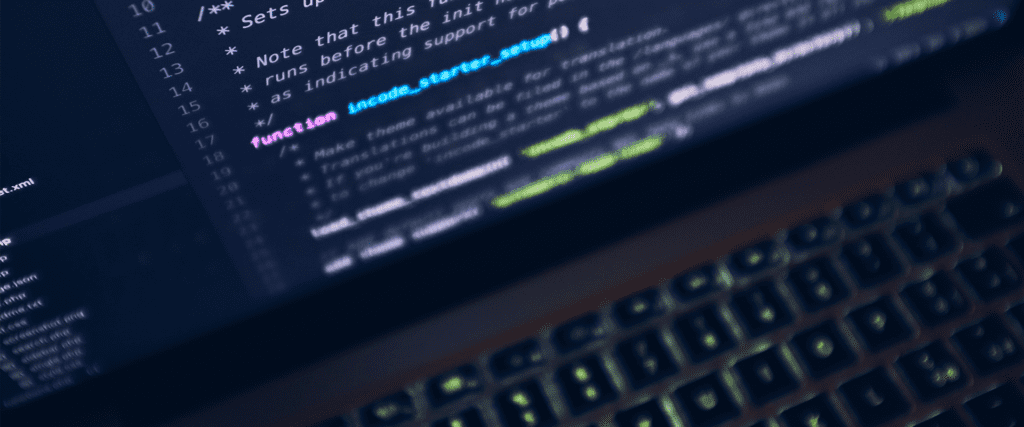 A close-up of a laptop keyboard with a screen displaying lines of code, featuring syntax highlighting in various colors.