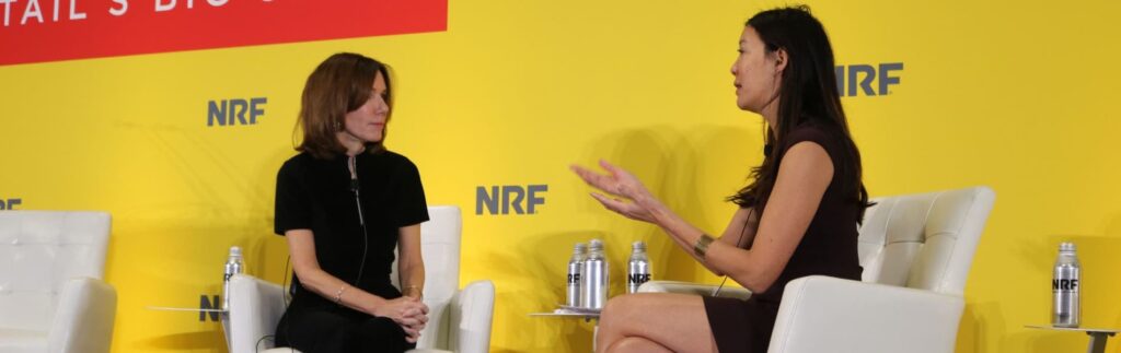 Two women seated and engaged in conversation on stage at an event, with "NRF" logos and a yellow background.