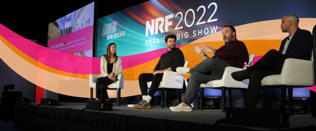 Four people sit on stage with large "NRF 2022: Retail's Big Show" signage in the background, having a panel discussion.