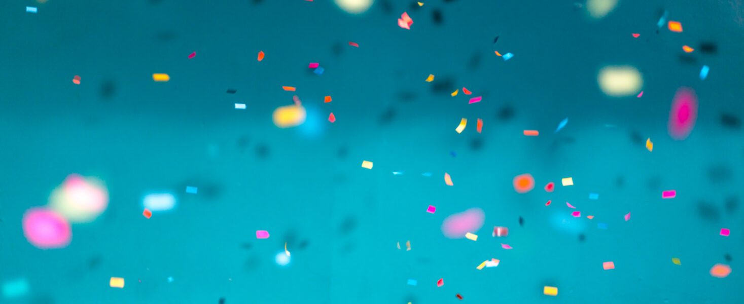 Multicolored confetti pieces are scattered against a blue background.