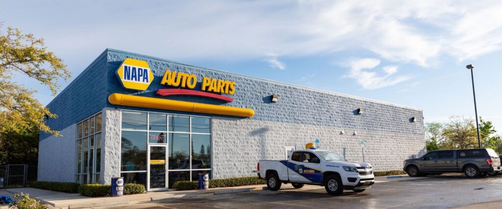 NAPA Auto Parts store with a branded pickup truck parked in front, under a clear sky.