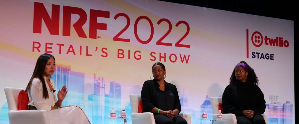 Three individuals participate in a panel discussion at NRF 2022: Retail’s Big Show on the Twilio Stage, seated in front of a branded backdrop.