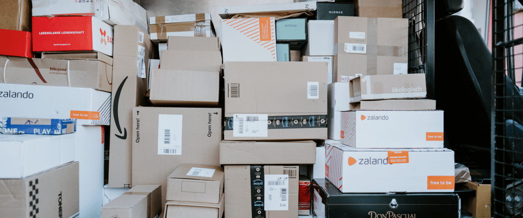 A stack of assorted delivery boxes from various brands, including Zalando, arranged inside a vehicle.