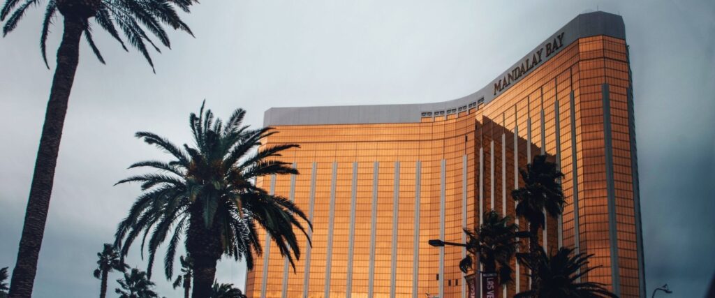 Golden building with "Mandalay Bay" sign surrounded by palm trees, against a stormy sky.