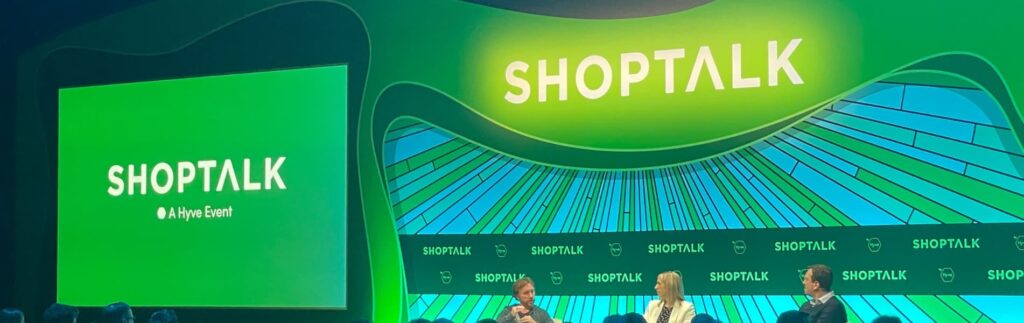 Three people sit on stage under a green "Shoptalk" sign at a discussion event. A large screen on the left also displays "Shoptalk" and "A Hyve Event.