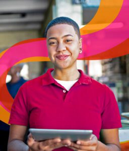 person holding device wearing pink shirt with colorful swirl in background