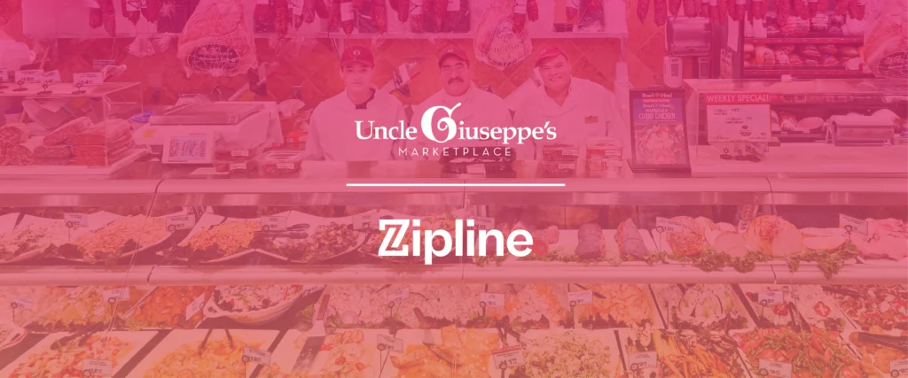 Three employees stand behind a deli counter at Uncle Giuseppe’s Marketplace, with various prepared foods displayed in front and meat products hanging in the background. Zipline logo is overlaid.