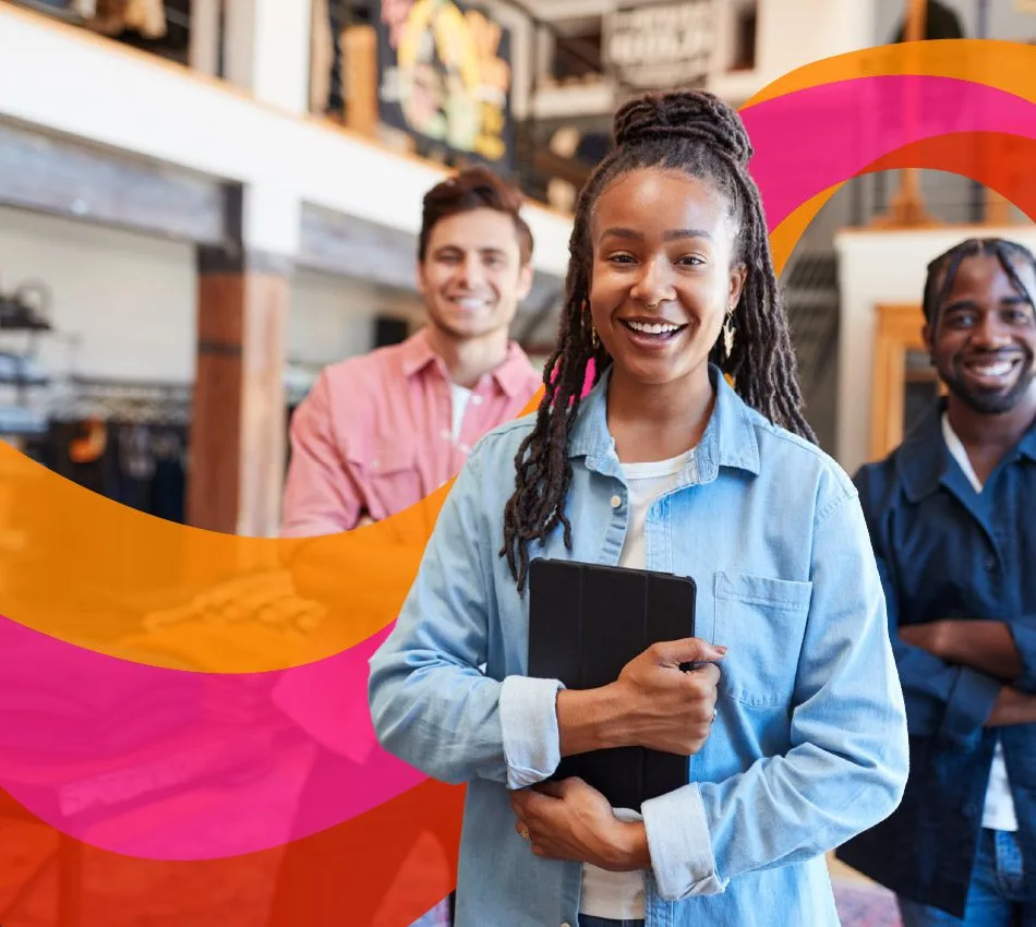 Three people stand smiling in a store. The person in front holds a tablet. Vibrant orange and pink graphic swirls are in the background.