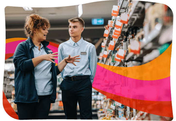 A woman and a young man in a store aisle engage in conversation. The aisle is lined with various products. A colorful graphic overlay is in the background.
