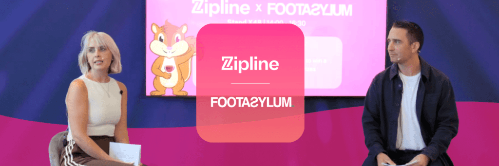 Two people sit on stage in front of a screen displaying "Zipline x Footasylum" with a cartoon character and event details in the background.