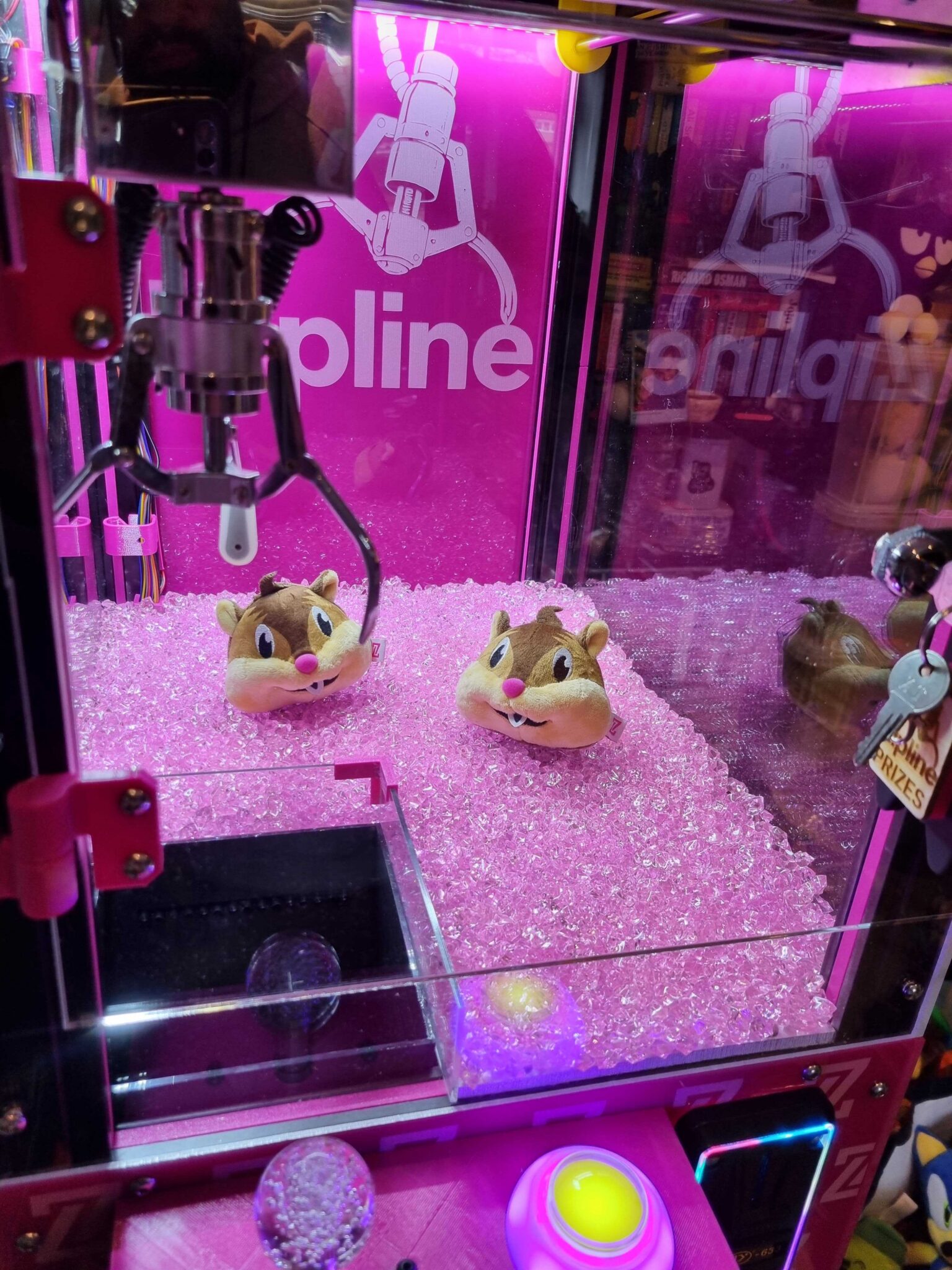 Inside Zippy: Getting Real-time Answers With MCP 1 Claw machine with two plush chipmunk toys on pink beads, surrounded by bright pink lighting and reflective surfaces.