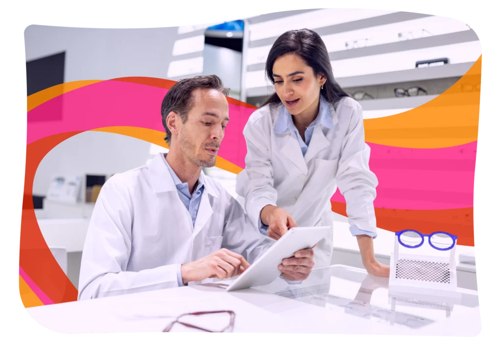 Two people in lab coats review information on a tablet at a modern eyewear store, with glasses and colorful abstract graphics in the background.
