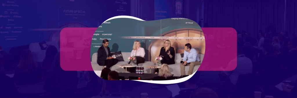 Four people sit on a stage during a panel discussion, with an audience watching from the darkened room.
